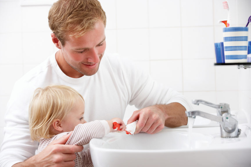 Father And Daughter In Bathroom Brushing Teeth Together